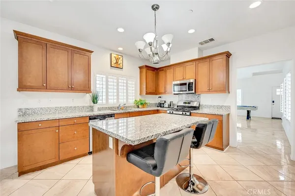 a kitchen with stainless steel appliances granite countertop wooden cabinets a stove a sink a dining table and chairs