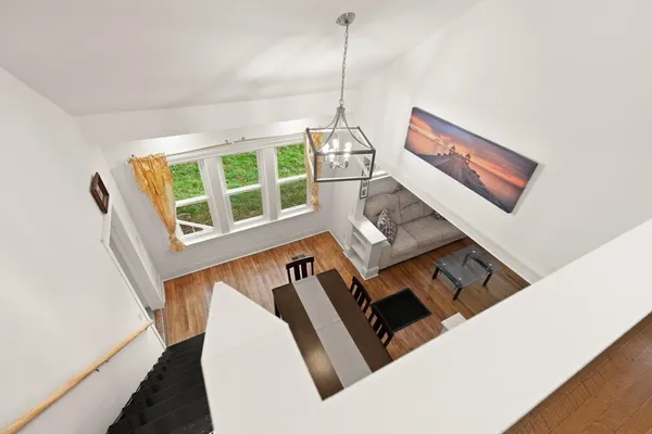 a view of a white house next to a yard with plants and trees