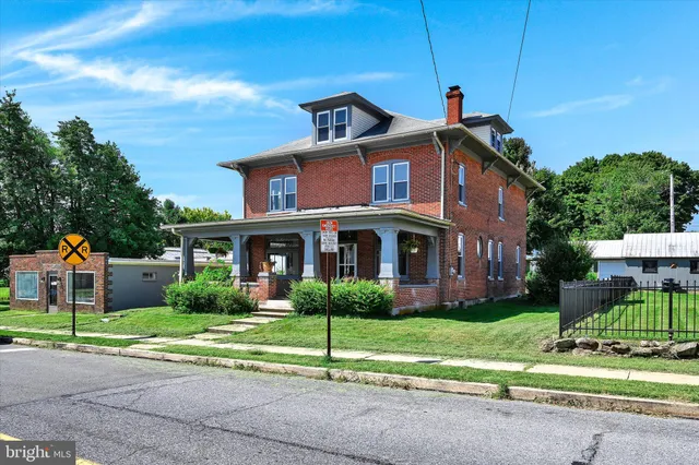 a front view of a house with a yard and potted plants