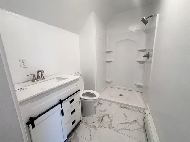 a bathroom with a granite countertop sink a toilet and shower
