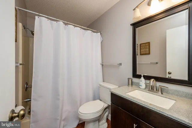 a bathroom with a granite countertop sink toilet and a mirror