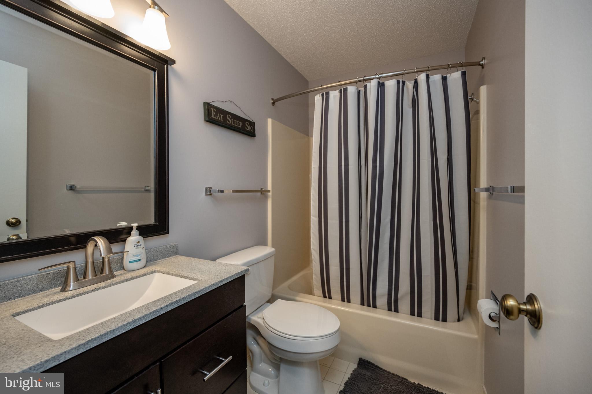 48 Bright Passage, Unit 5B McHenry, MD 21541 - Photo 24 of 56 a bathroom with a granite countertop sink toilet a mirror and shower