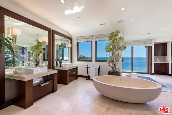 a spacious bathroom with a tub a sink and mirror