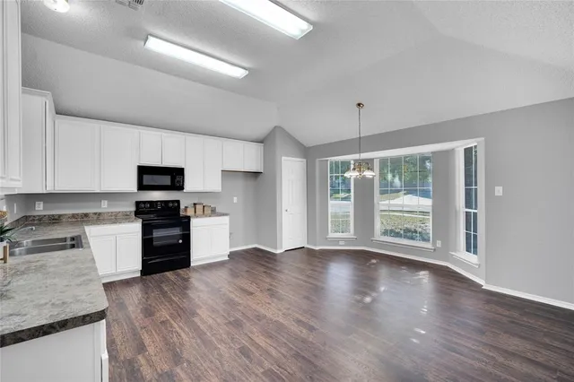 a kitchen with granite countertop stainless steel appliances and wooden floor