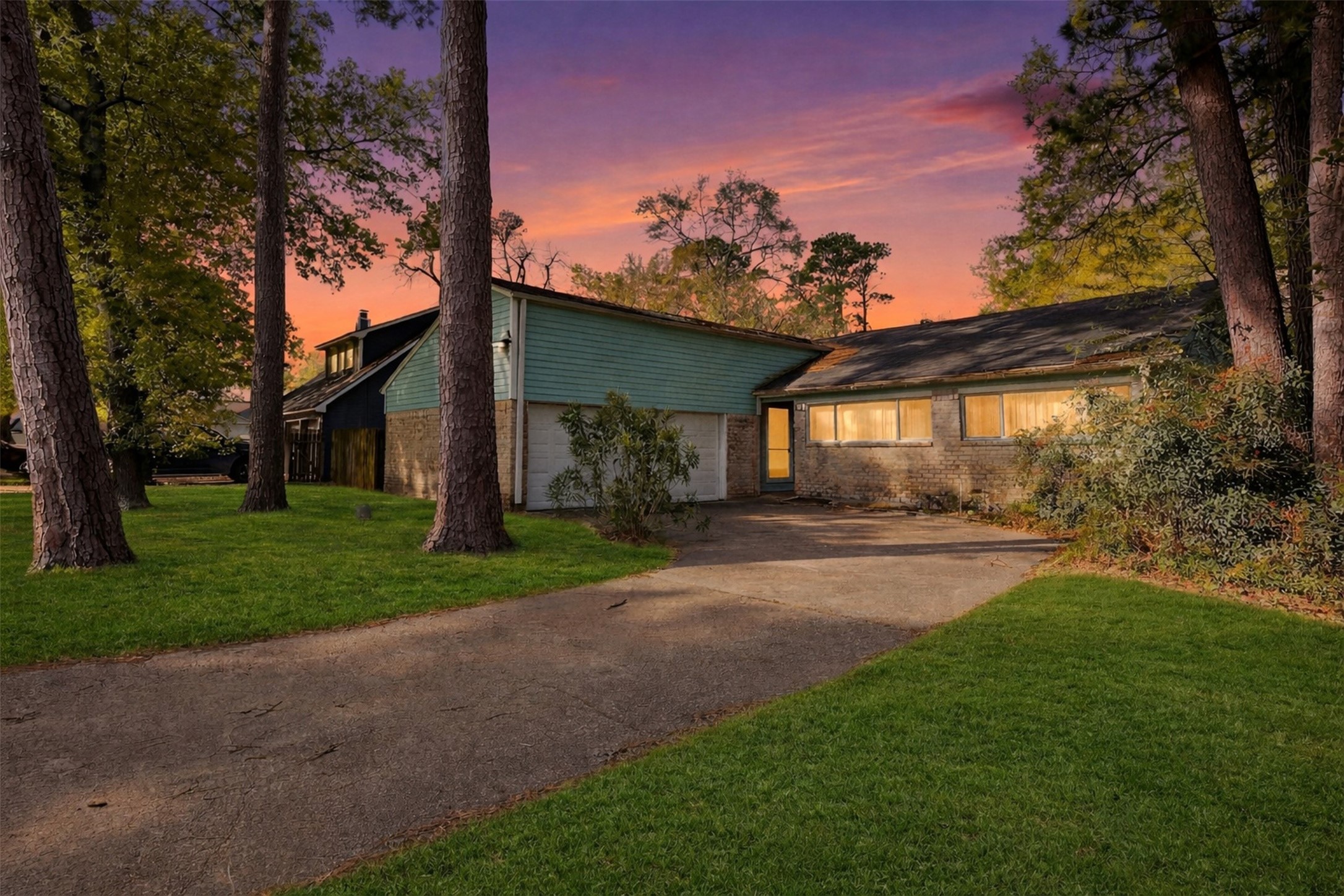 Welcoming front exterior with mature trees and an extended driveway offering excellent curb appeal.