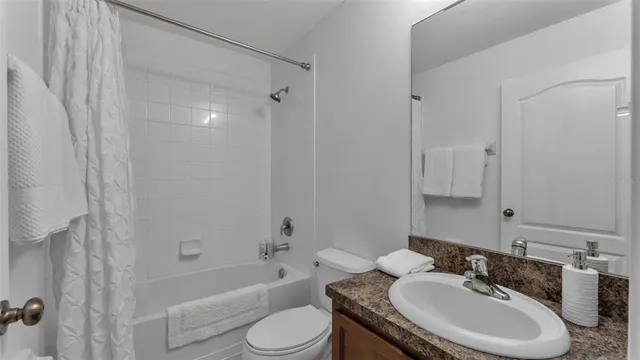 a bathroom with a granite countertop sink toilet a mirror a bathtub and shower