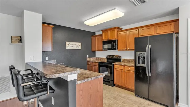 a kitchen with stainless steel appliances kitchen island a table chairs microwave and refrigerator