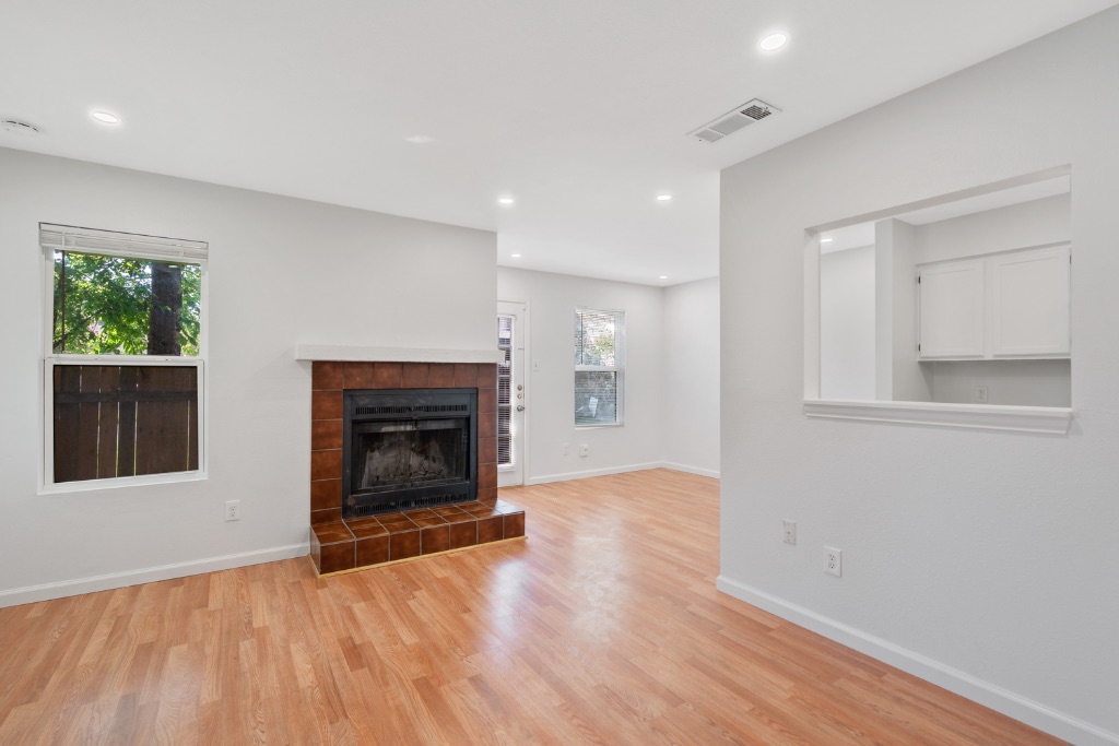 8703 Schick Road, Unit A Austin, TX 78729 - Photo 2 of 21 an empty room with wooden floor fireplace and windows