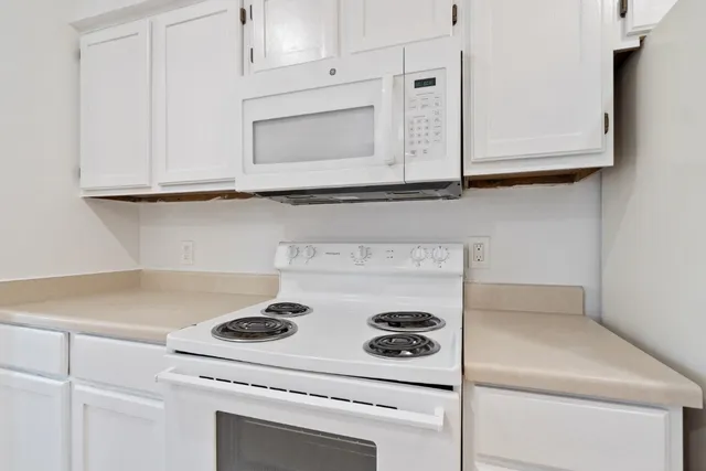 a kitchen with white cabinets and white appliances