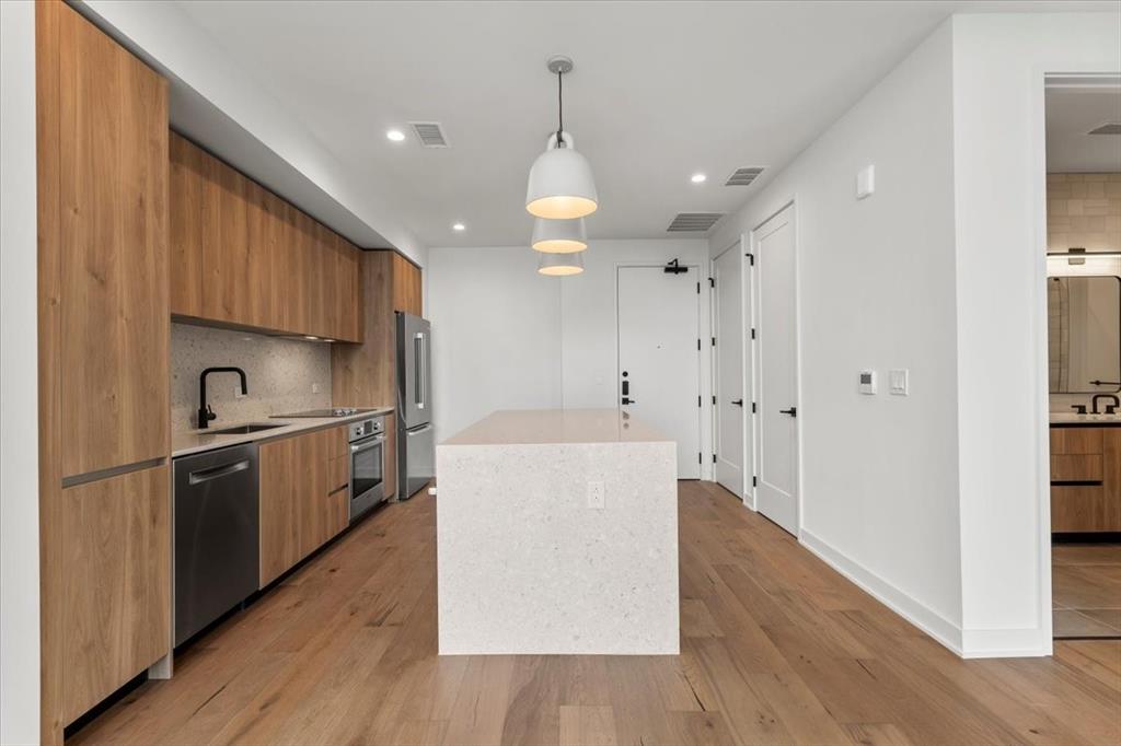 84 East Avenue, Unit 1202 Austin, TX 78701 - Photo 5 of 39 a kitchen with stainless steel appliances granite countertop a refrigerator a sink dishwasher a stove and white countertops with wooden floor