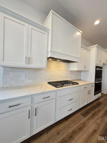 a kitchen with granite countertop white cabinets and white appliances