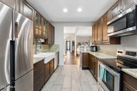 a kitchen with stainless steel appliances granite countertop a refrigerator a stove and a sink