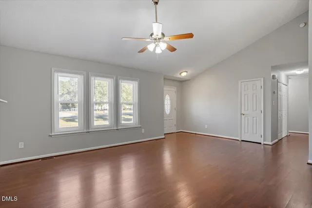 a view of an empty room with wooden floor and a window