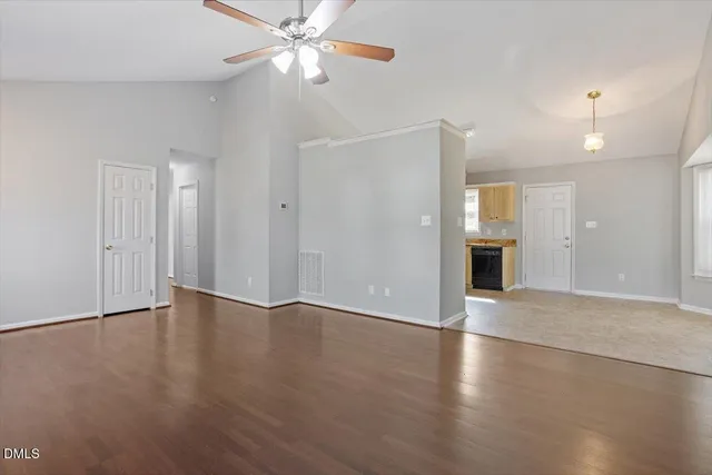 an empty room with wooden floor fan and windows