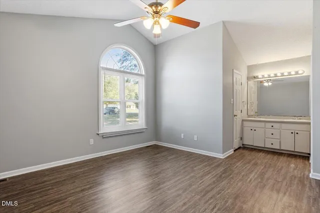 an empty room with wooden floor fan and window