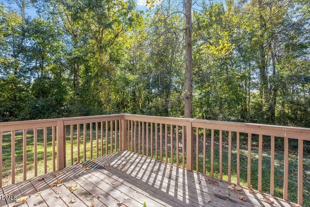 a balcony with wooden floor and trees in the background
