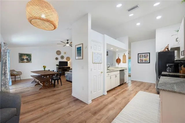 a kitchen with stainless steel appliances granite countertop a stove a sink a refrigerator and a dining table with wooden floor