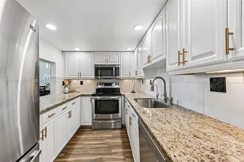 a large kitchen with stainless steel appliances granite countertop a sink and dishwasher a stove top oven with wooden floor