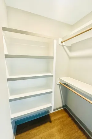 an empty room with wooden floor closet and windows
