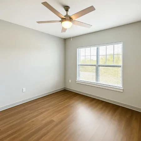 an empty room with wooden floor and a ceiling fan