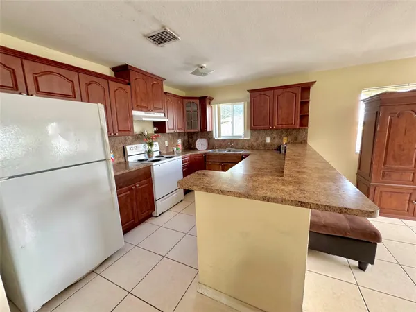 a kitchen with granite countertop a refrigerator a stove a sink a washer and dryer