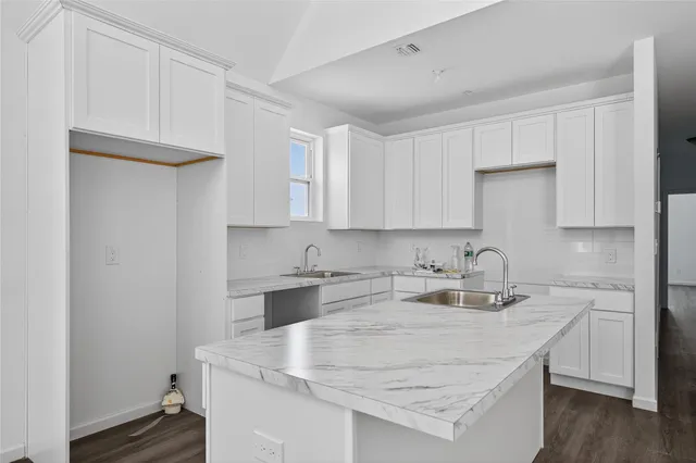 a kitchen with kitchen island a sink a stove and cabinets