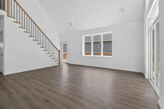 a view of an empty room with wooden floor and windows