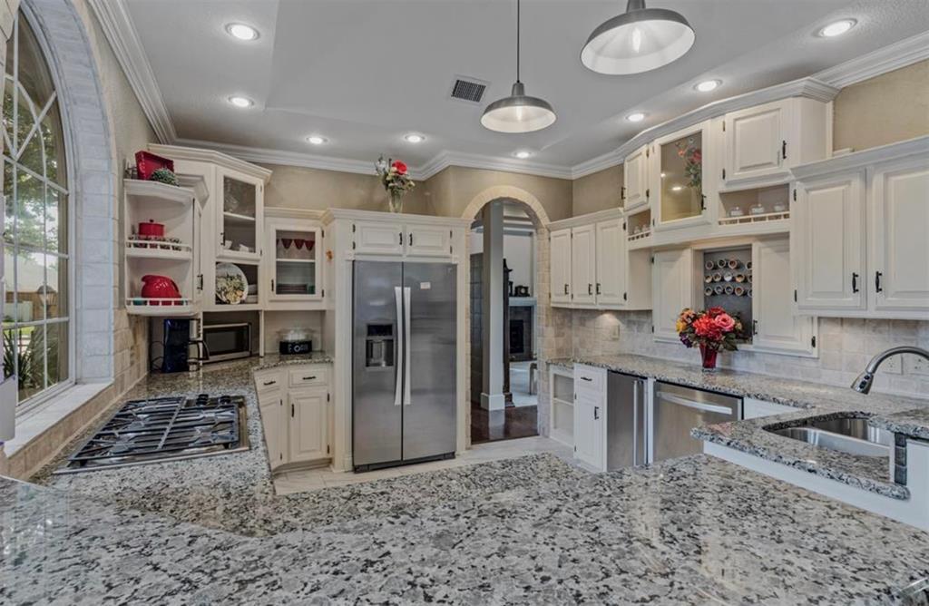 1450 Meandering Way Rockwall, TX 75087 - Photo 13 of 32 a kitchen with stainless steel appliances granite countertop a sink and a refrigerator