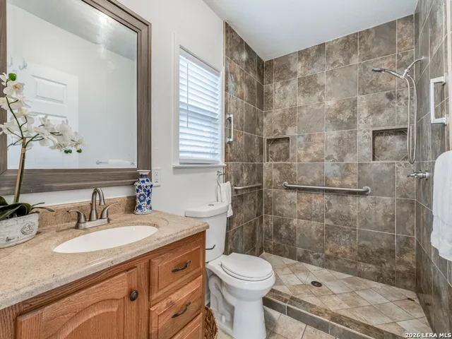 a bathroom with a granite countertop sink a toilet and shower