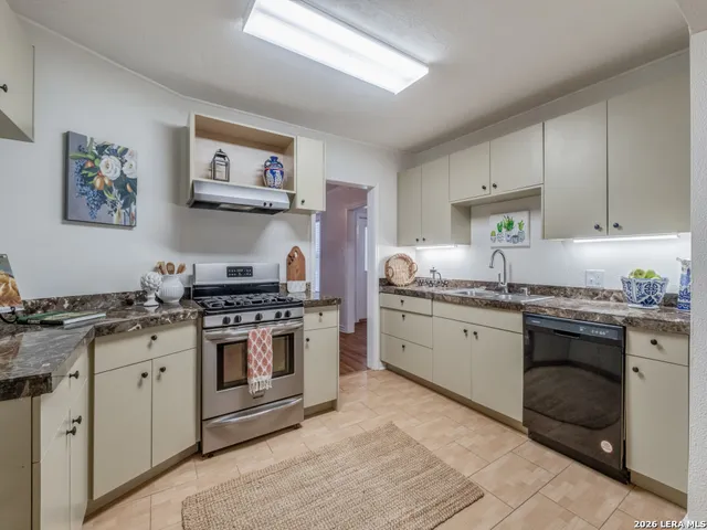 a kitchen with granite countertop stainless steel appliances a stove sink and cabinets