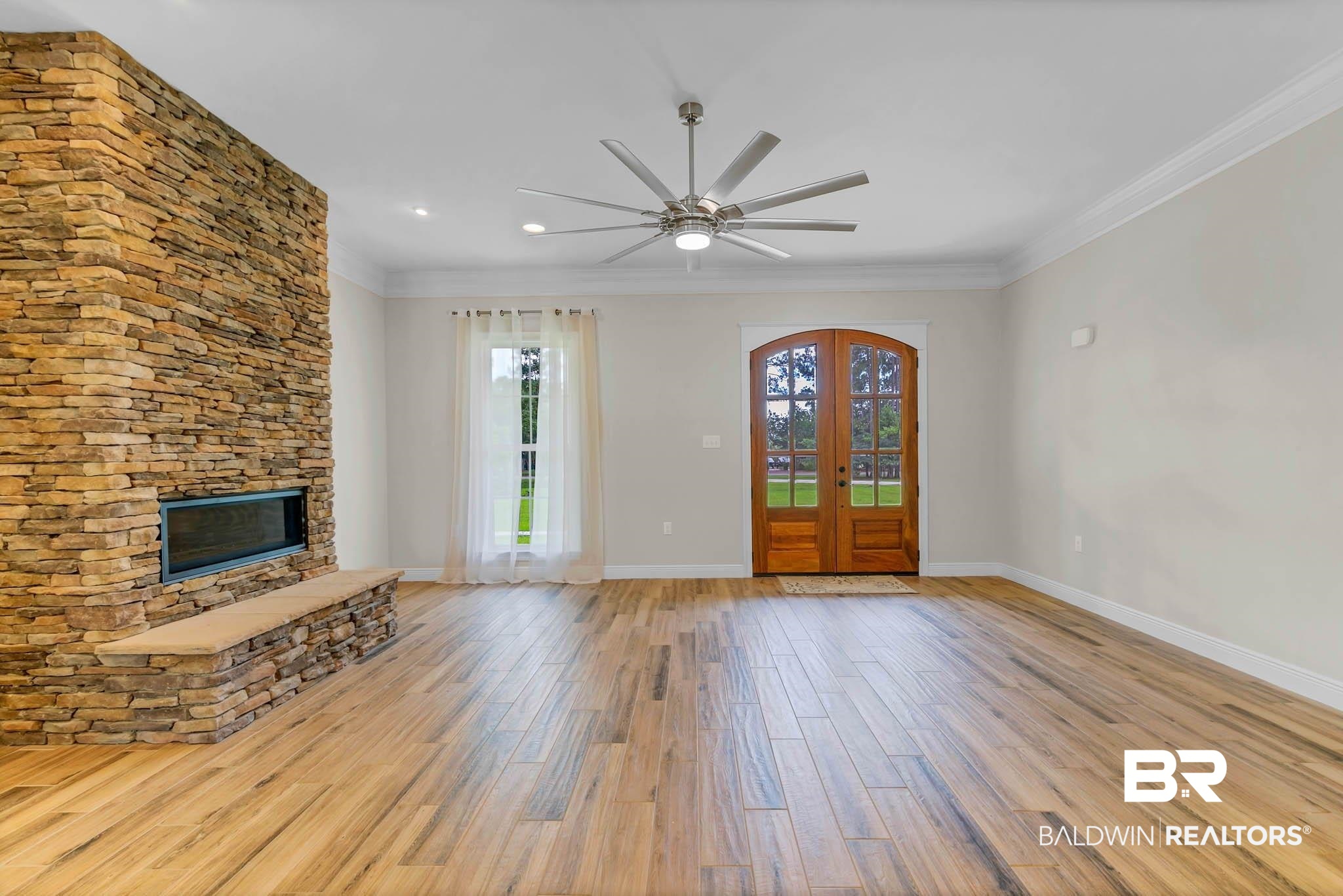 8145 Bay View Drive Foley, AL 36535 - Photo 9 of 81 Unfurnished living room with wood finished floors, a stone fireplace, a ceiling fan, crown molding, and recessed lighting
