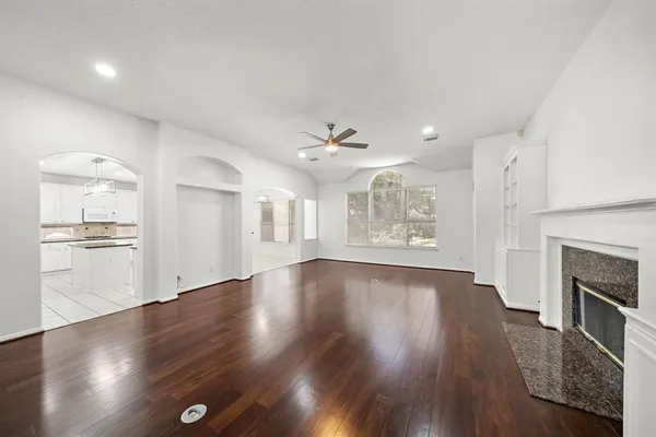 an empty room with wooden floor fireplace and windows