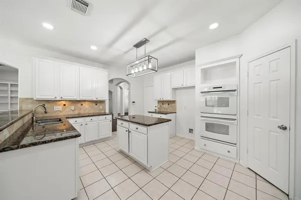 a kitchen with granite countertop a stove sink and cabinets