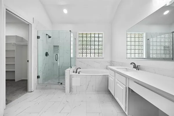 a spacious bathroom with a tub sink shower and mirror