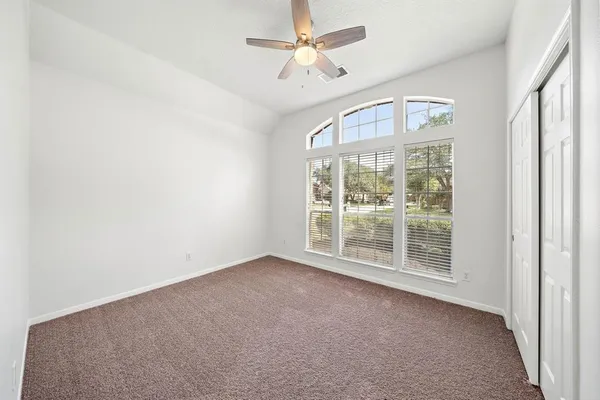 an empty room with windows and fan