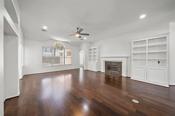 a view of an empty room with a fireplace and wooden floor