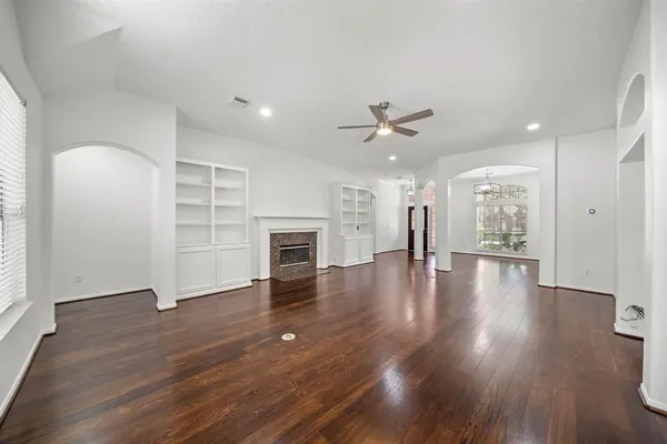 an empty room with wooden floor fireplace and windows