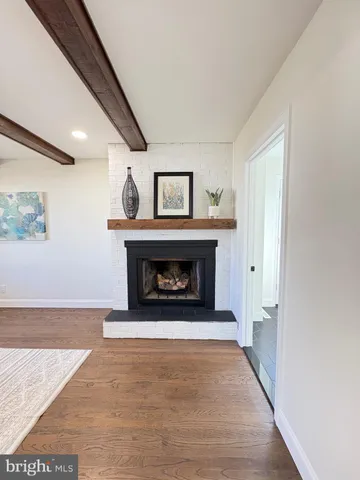 a view of an empty room with wooden floor fireplace and a window