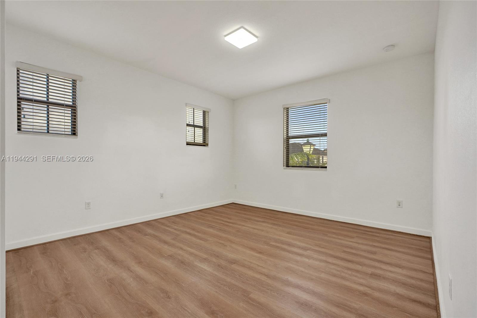 3504 West 94th Street Hialeah, FL 33018 - Photo 49 of 61 an empty room with wooden floor and windows