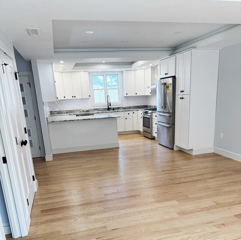 17 Fremont Street, Unit 1 Somerville, MA 02145 - Photo 6 of 7 a kitchen with stainless steel appliances a refrigerator and wooden floor