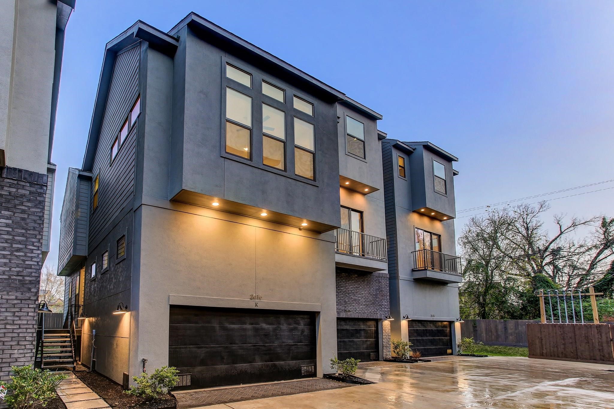 2616 Riverside Drive, Unit K Houston, TX 77004 - Photo 1 of 31 Modern two-story townhouse with sleek, contemporary design. Features large windows, a two-car garage, and a small balcony. The exterior showcases clean lines and stylish lighting, set in a quiet neighborhood with minimal landscaping.
