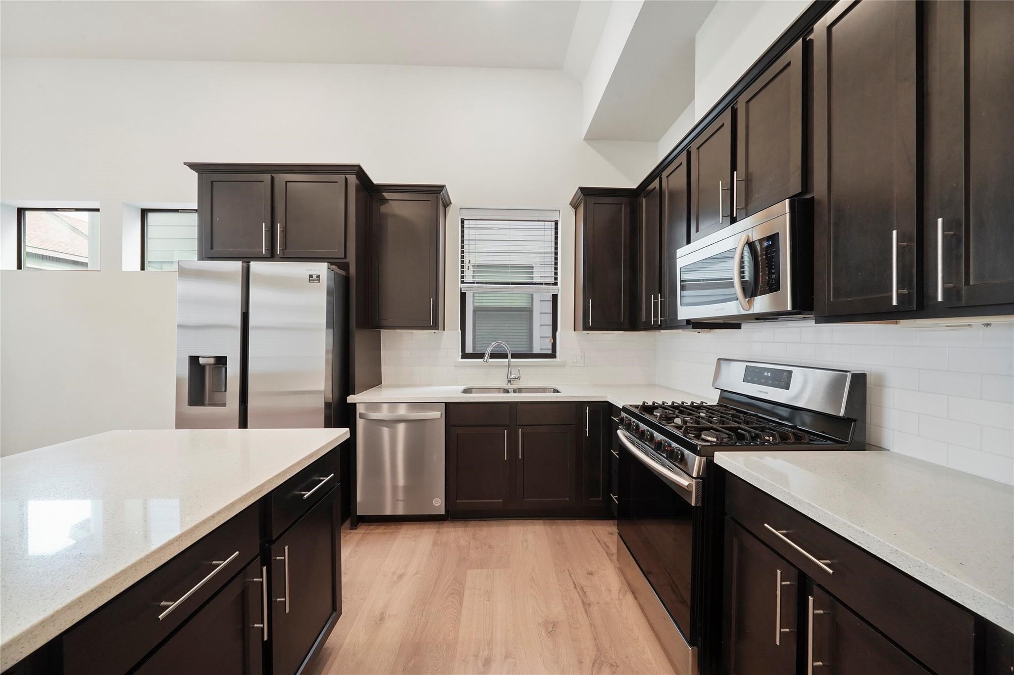 2616 Riverside Drive, Unit K Houston, TX 77004 - Photo 18 of 31 This modern kitchen features sleek dark cabinetry, stainless steel appliances, and light countertops. It has a spacious layout with a central island, a large gas stove, and ample natural light from multiple windows.