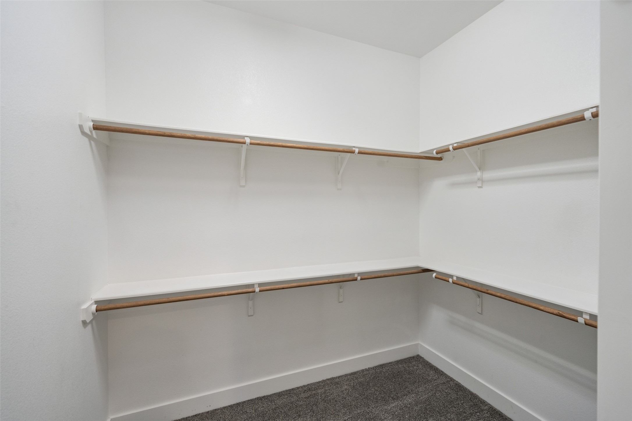 2616 Riverside Drive, Unit K Houston, TX 77004 - Photo 23 of 31 This photo showcases a spacious walk-in closet with multiple wooden shelves and rods for ample storage and organization, featuring clean white walls and a carpeted floor.