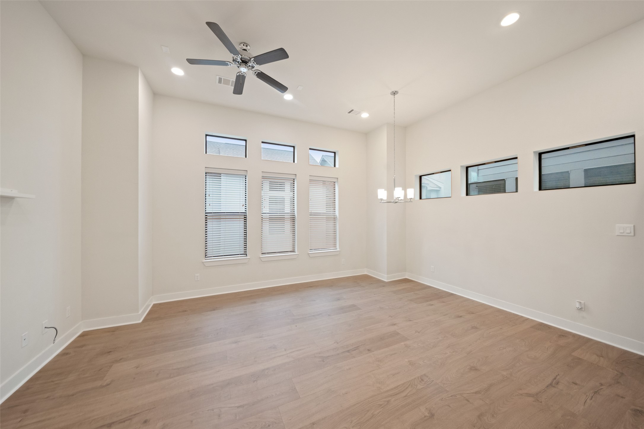 2616 Riverside Drive, Unit K Houston, TX 77004 - Photo 9 of 31 Bright, spacious room with high ceilings, modern ceiling fan, and elegant pendant lighting. Features large windows allowing natural light to flow in, and sleek hardwood flooring. Ideal for a living or dining area.
