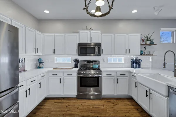 a kitchen with stainless steel appliances granite countertop white cabinets a stove a sink and dishwasher