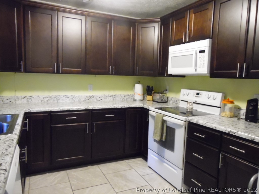 6799 Faircloth Bridge Road Stedman, NC 28391 - Photo 9 of 25 a kitchen with granite countertop stainless steel appliances a stove sink and cabinets