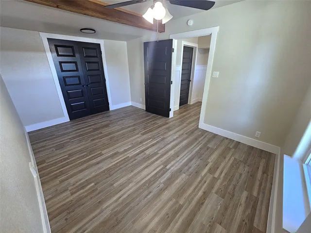 a view of an empty room with closet and wooden floor