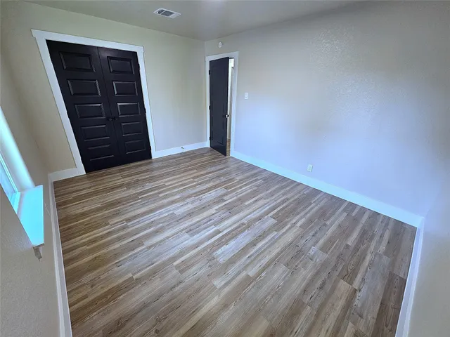 a view of empty room with closet and wooden floor