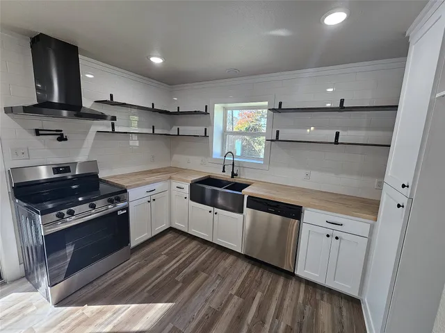 a kitchen with stainless steel appliances granite countertop a sink a stove and cabinets