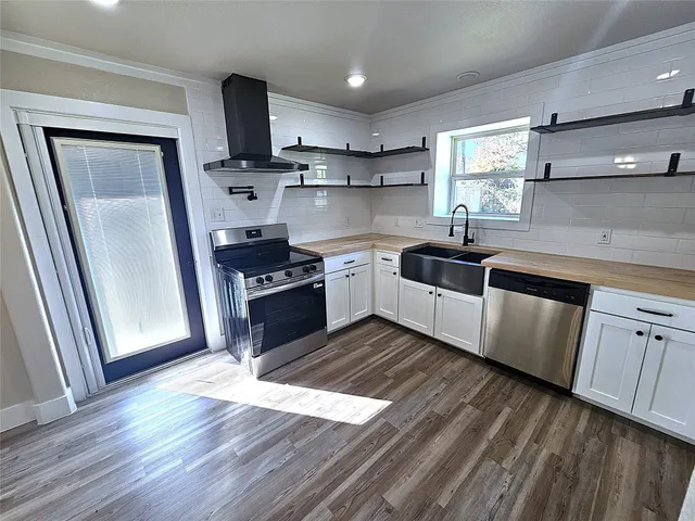 a kitchen with stainless steel appliances granite countertop a sink a stove a refrigerator and wooden floors